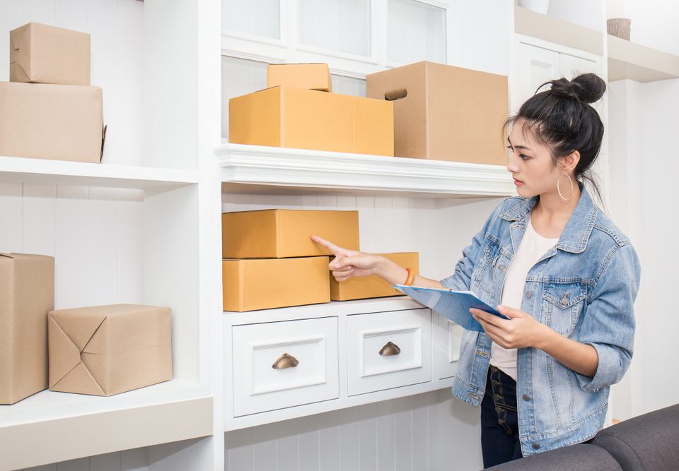 woman looking at boxes and an inventory list